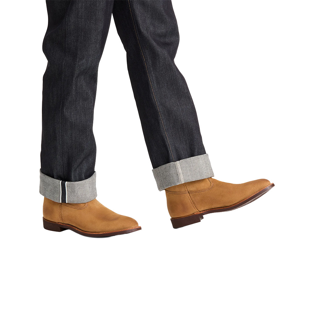 Brown leather boots worn with dark jeans on a white background
