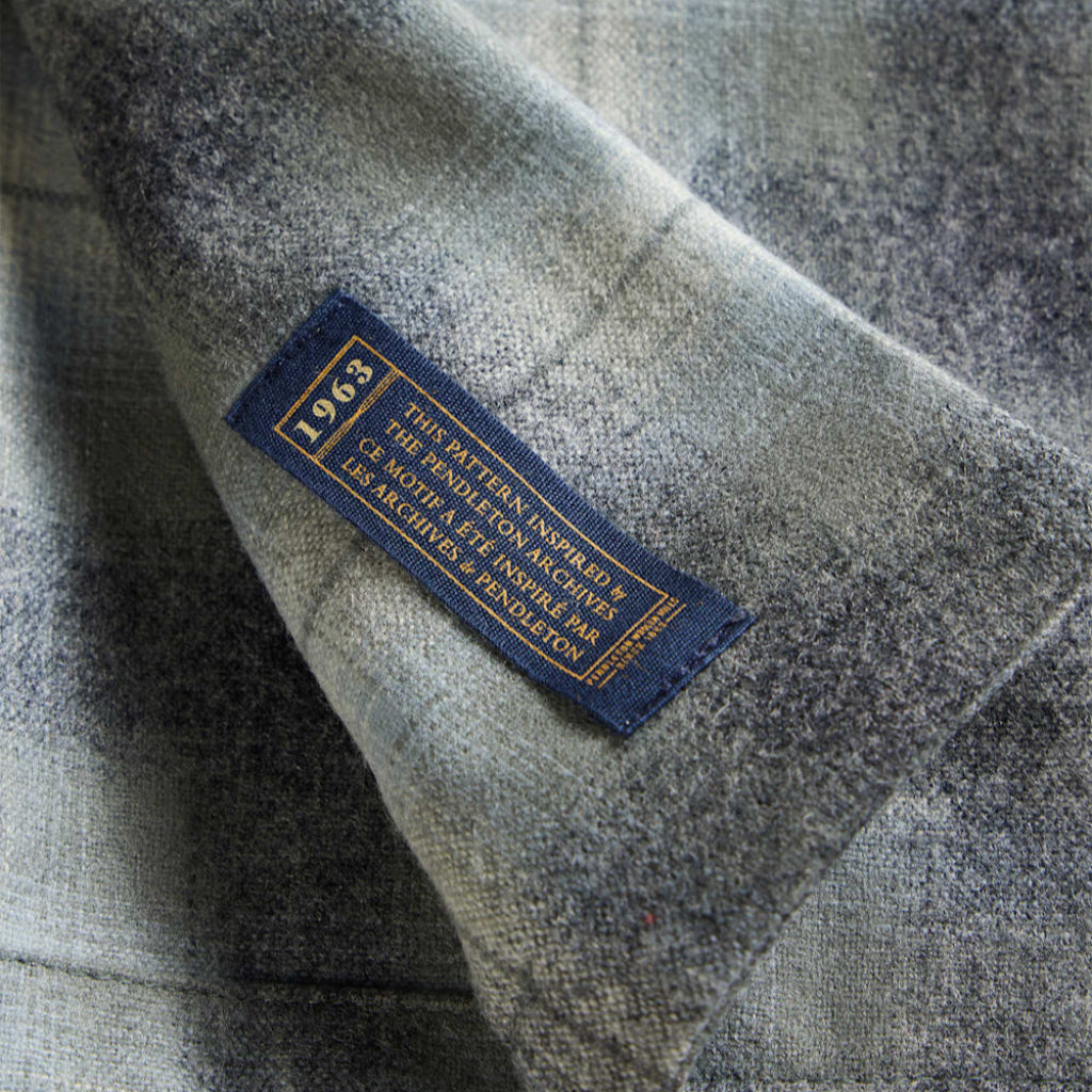 Close-up of a label on a plaid fabric with a brand logo.