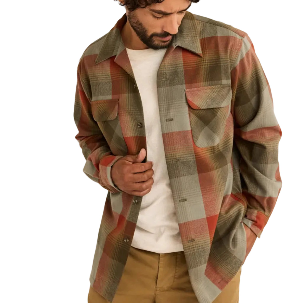 Man wearing a plaid shirt over a white t-shirt on a plain background