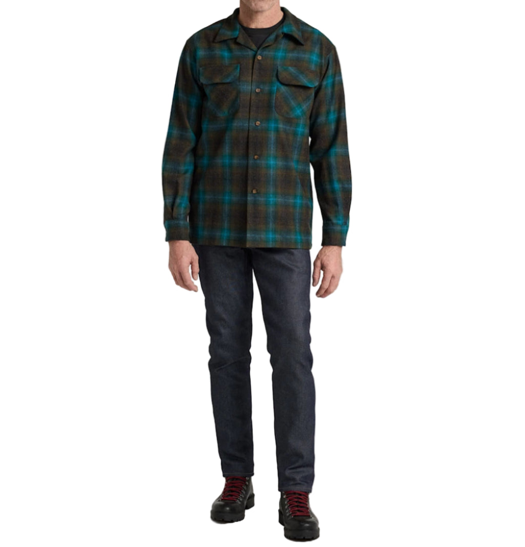 Person wearing a plaid shirt and dark pants on a white background