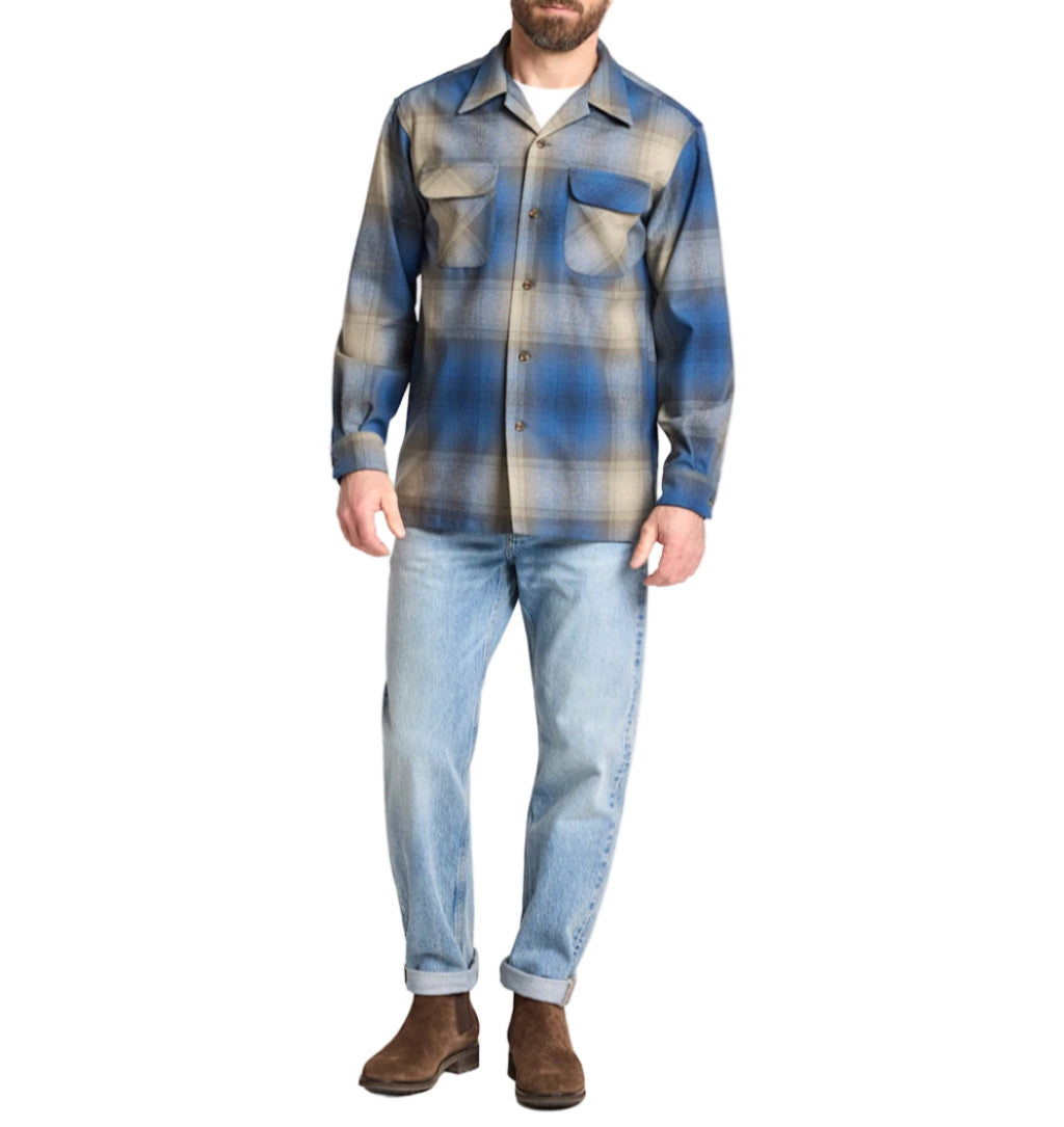 Man wearing a blue plaid shirt and jeans on a white background