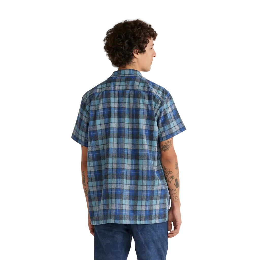Person wearing a blue plaid shirt and denim shorts on a white background