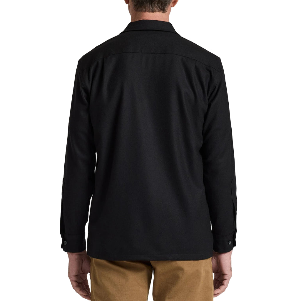 Man wearing a black shirt and brown pants against a white background