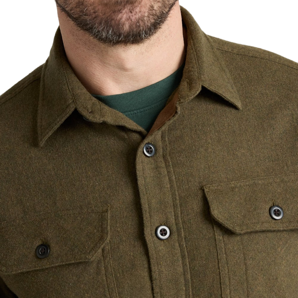 Close-up of a person wearing a green shirt with button details on a plain background