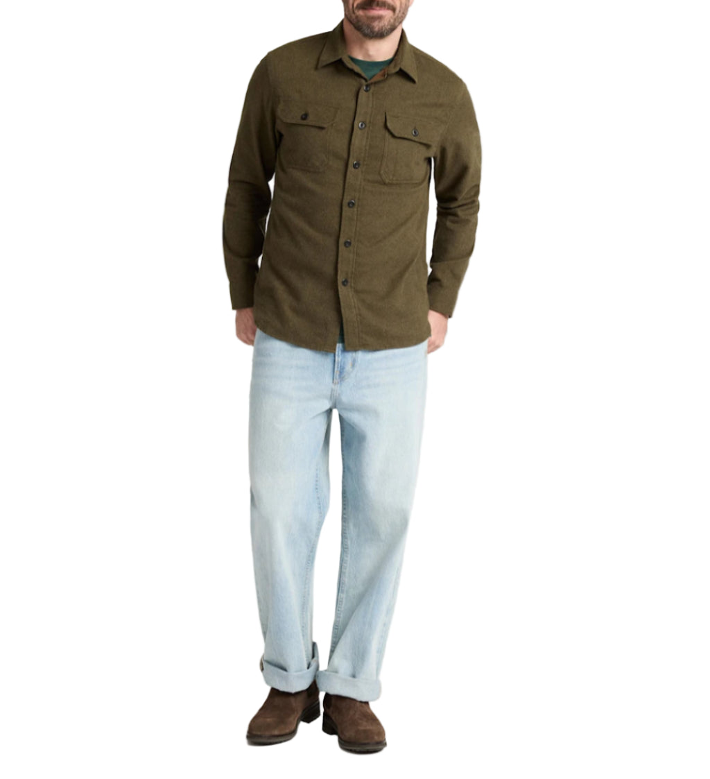 Man wearing a green shirt and light blue jeans on a white background