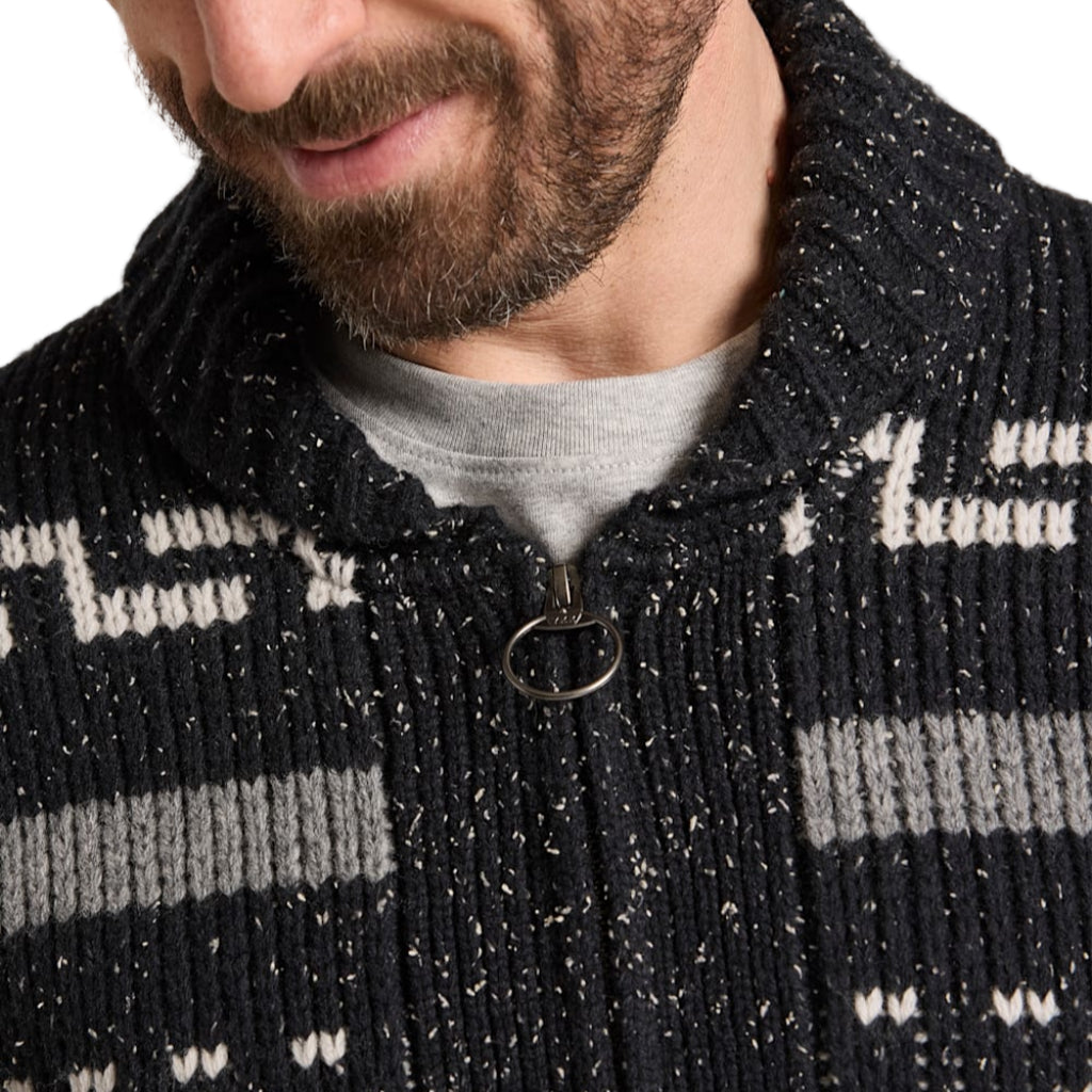 Close-up of a person wearing a black and gray patterned jacket with a zipper.