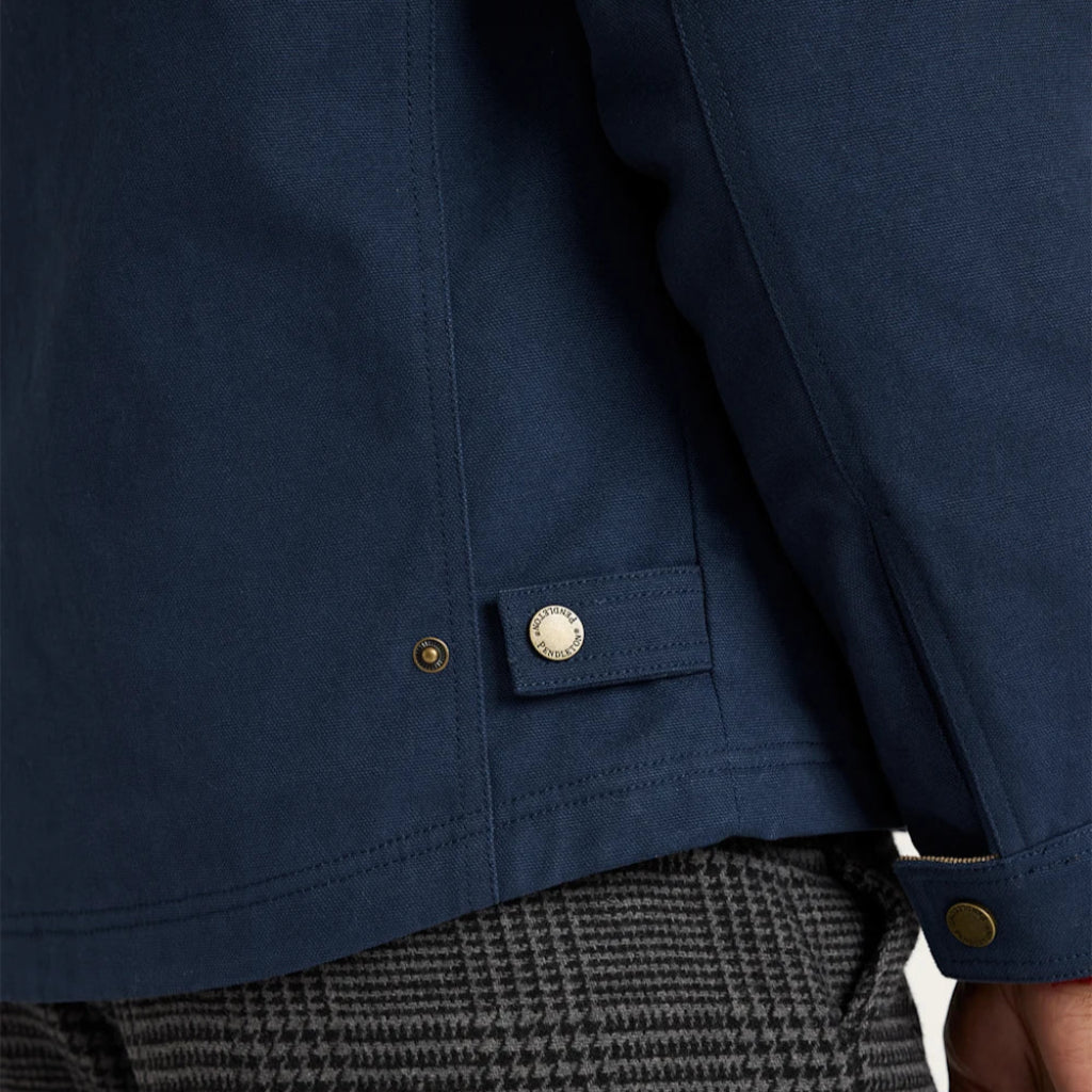 Close-up of a blue jacket with a button and a person wearing gray pants.