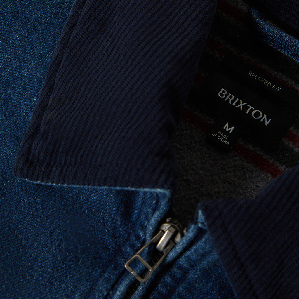 Close-up of a navy jacket with a Brixton label on a blue background