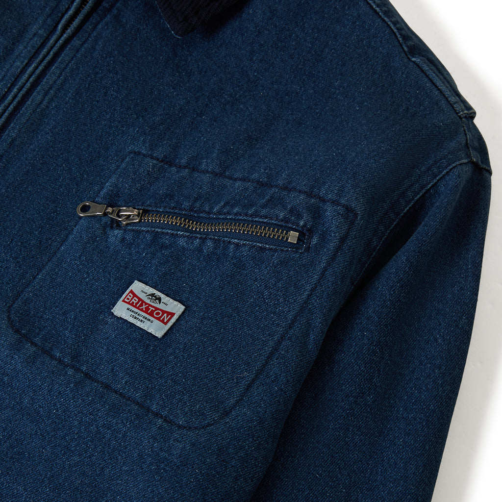 Close-up of a blue jacket with a zipper pocket and Brixton logo on a white background