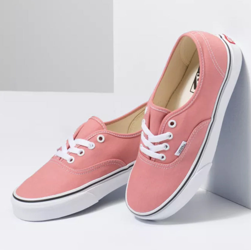 Pair of pink sneakers with white laces on a light gray background