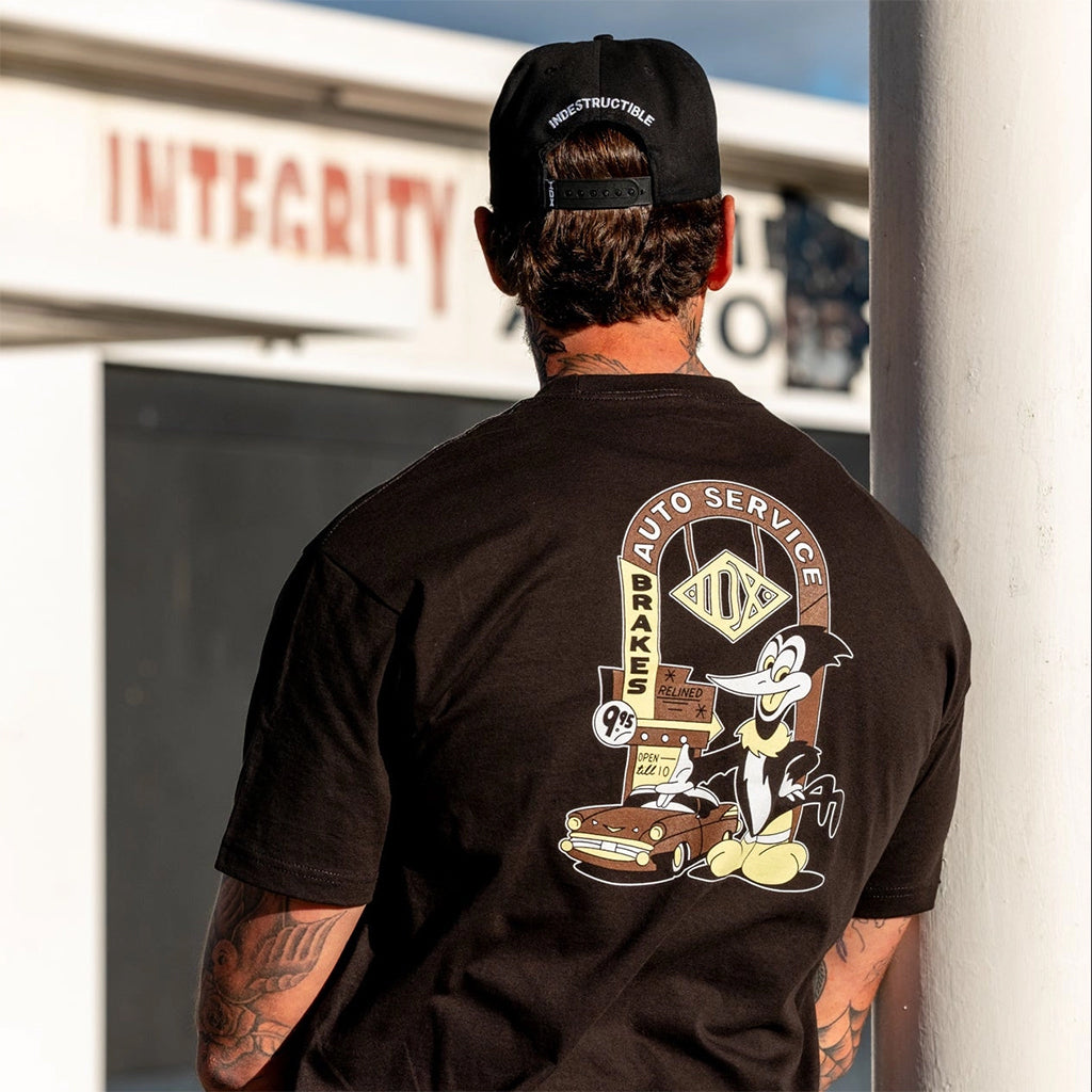Person wearing a black t-shirt with a graphic design on the back, standing in front of a building