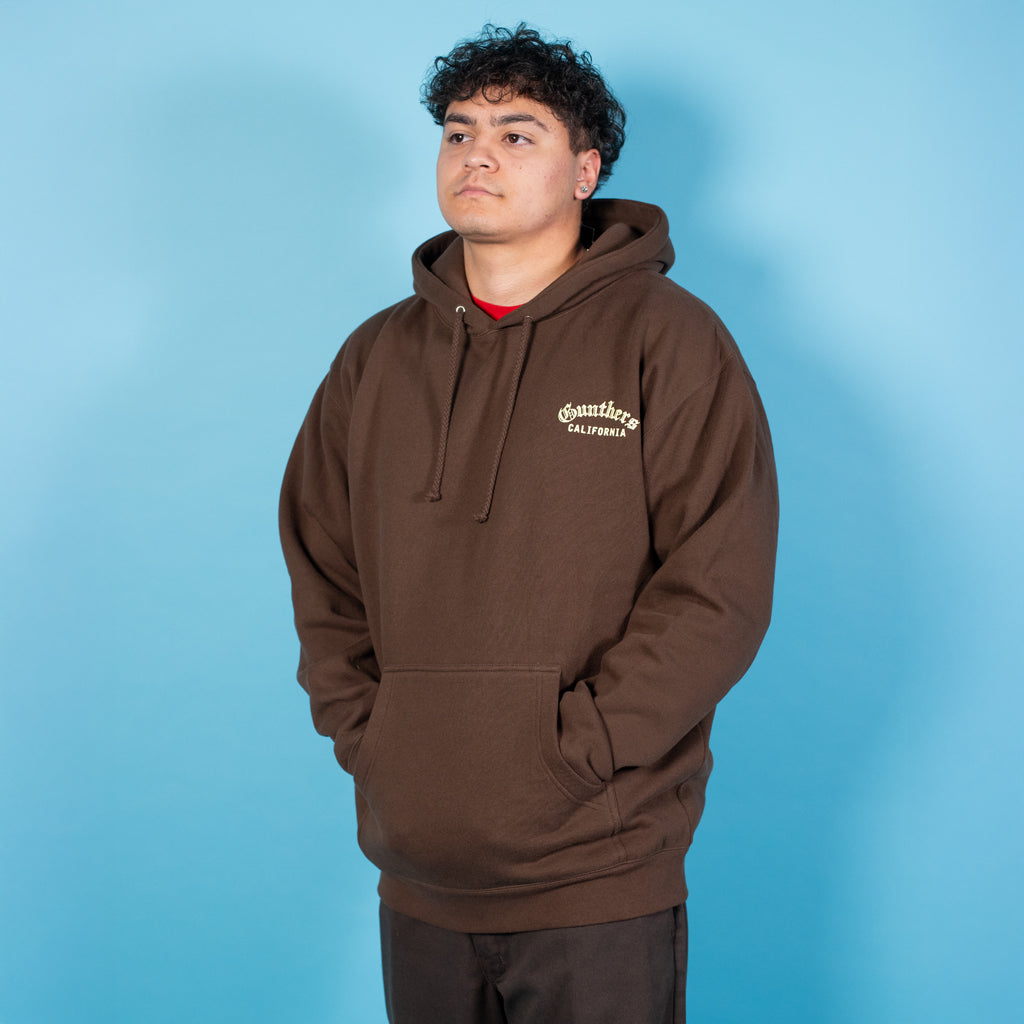 Person wearing a brown hoodie with a logo on a blue background