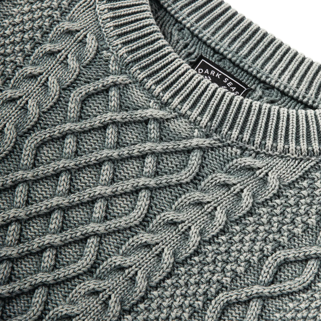 Close-up of a textured sweater with a brand label visible.