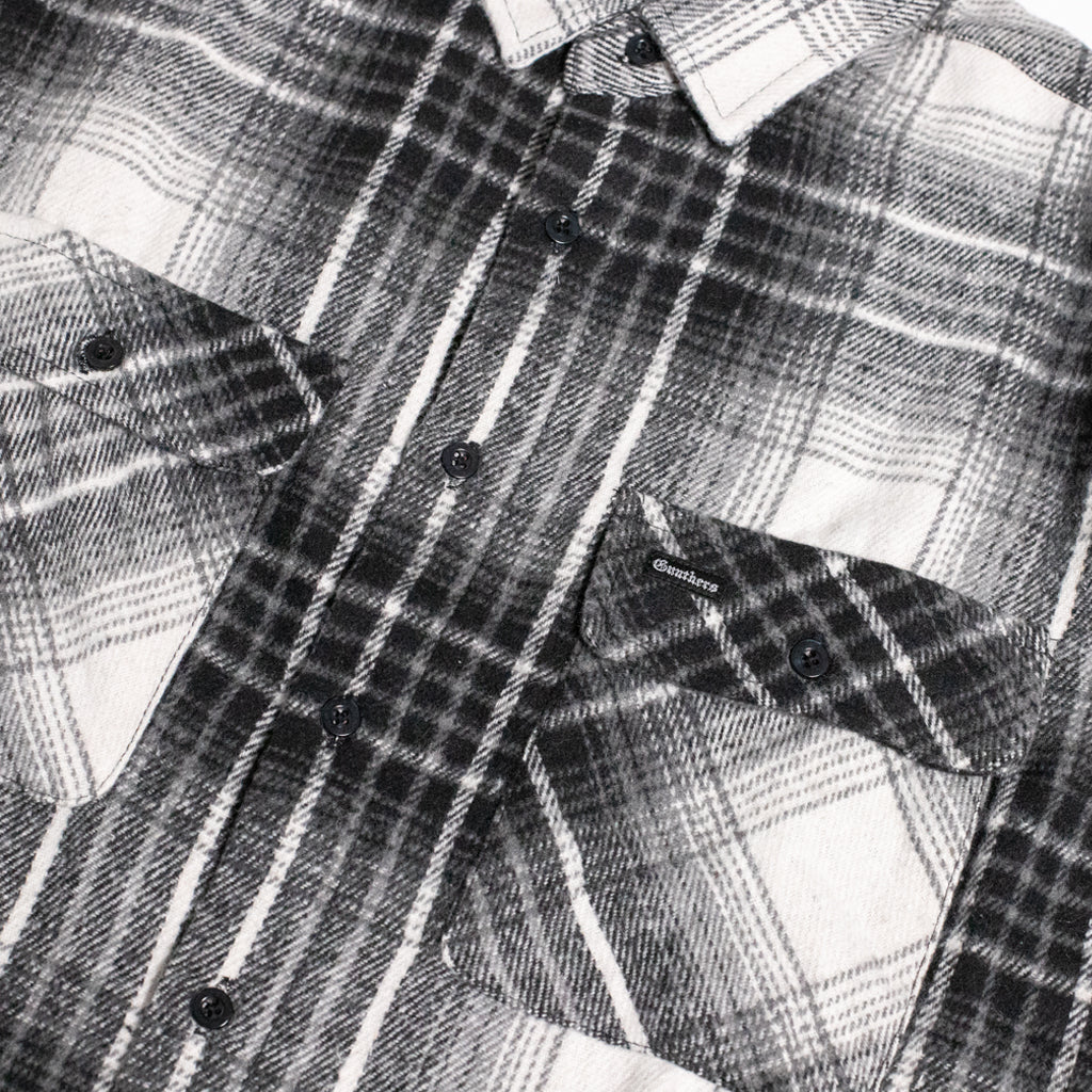 Close-up of a black and white plaid button-down shirt with two chest pockets and dark buttons.