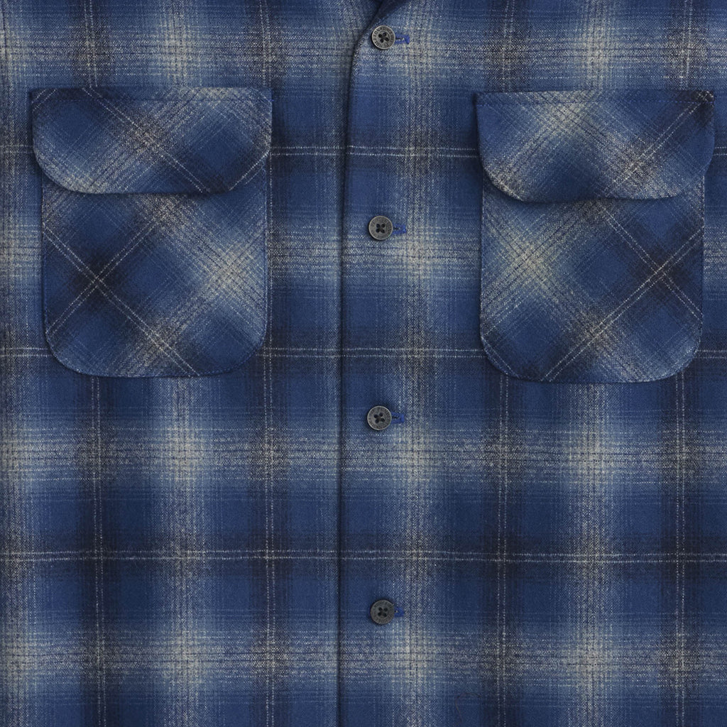 Close-up of a blue plaid shirt with two front pockets.