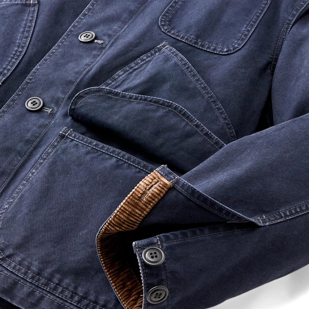 Close-up of a blue denim shirt with brown trim on a white background