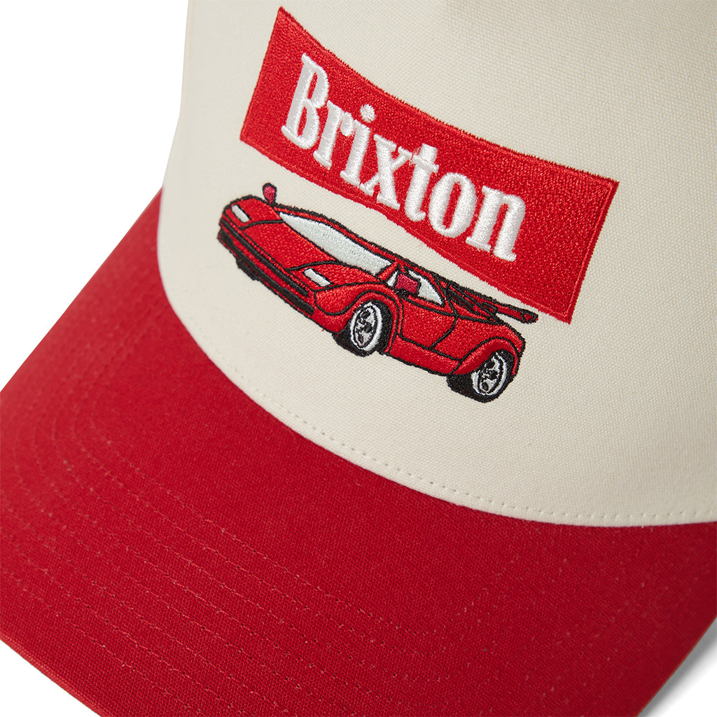 Red and beige cap with Brixton logo and car illustration on a white background