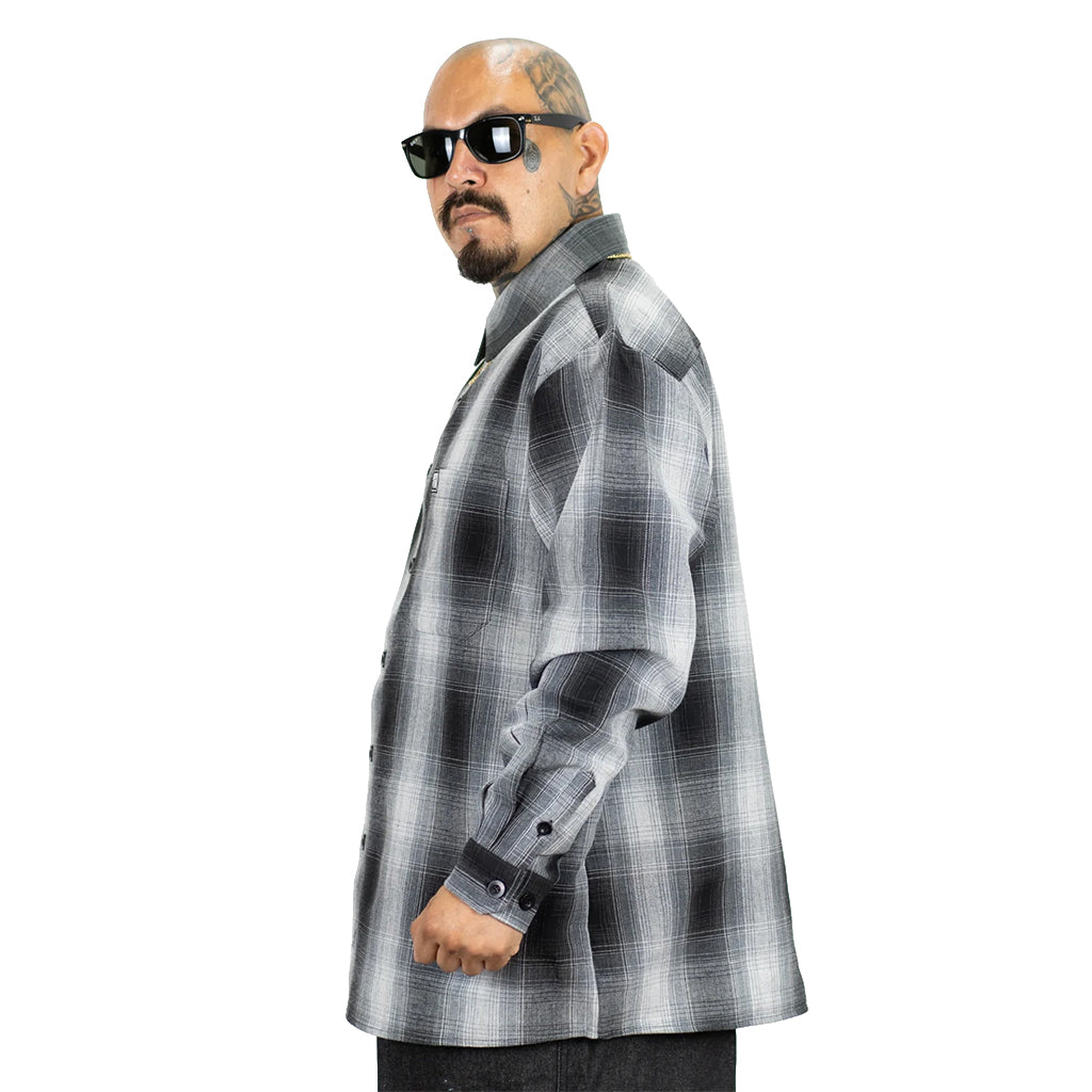 Man wearing a gray plaid shirt and sunglasses on a white background
