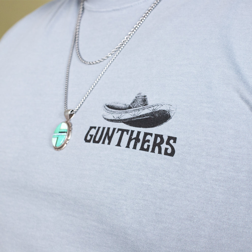 Gray t-shirt with 'GUNTHERS' logo and necklace on a plain background