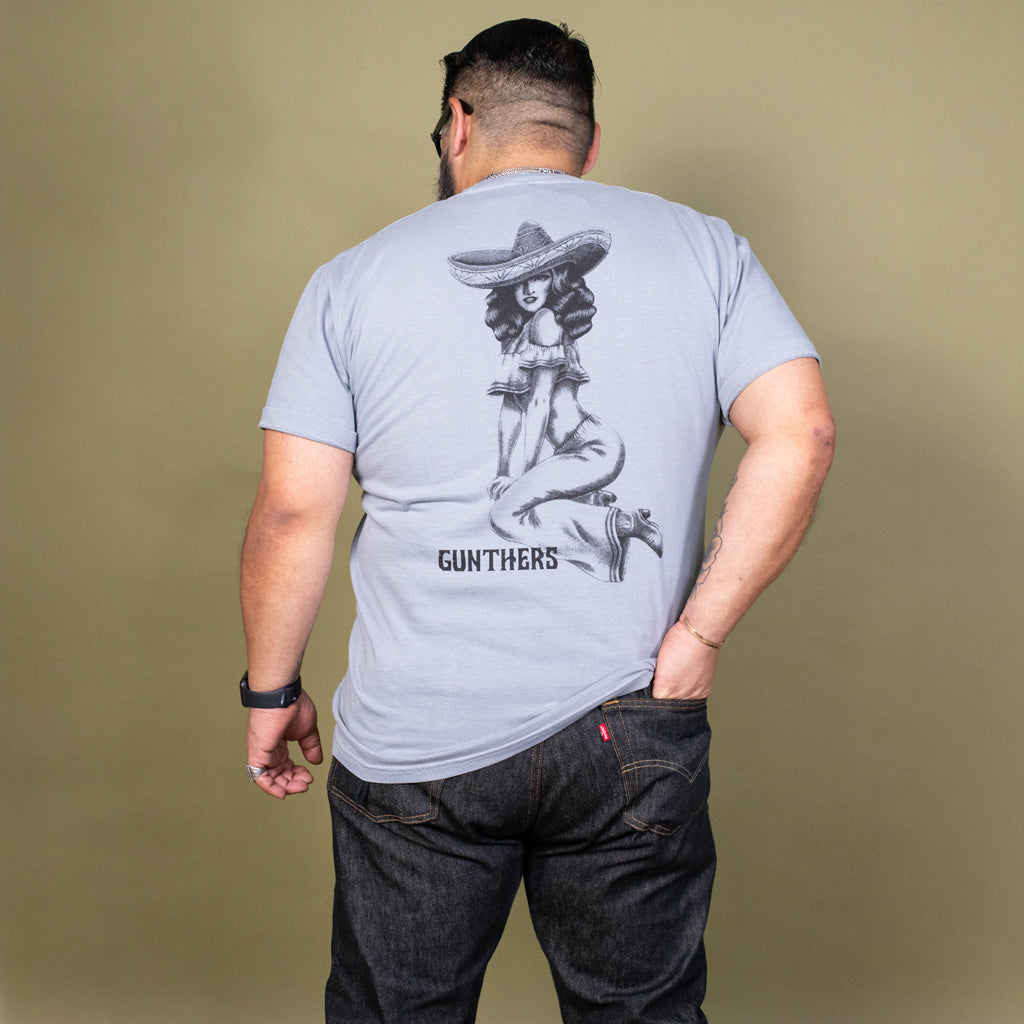 Man wearing a light blue t-shirt with a graphic design on the back against a beige background