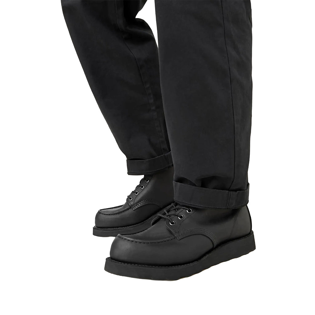 Black leather shoes worn with black pants on a white background