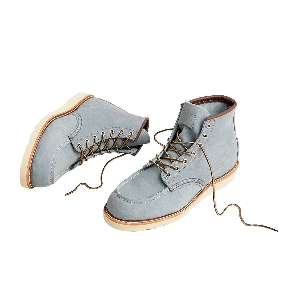 Pair of light blue suede boots with brown laces on a white background