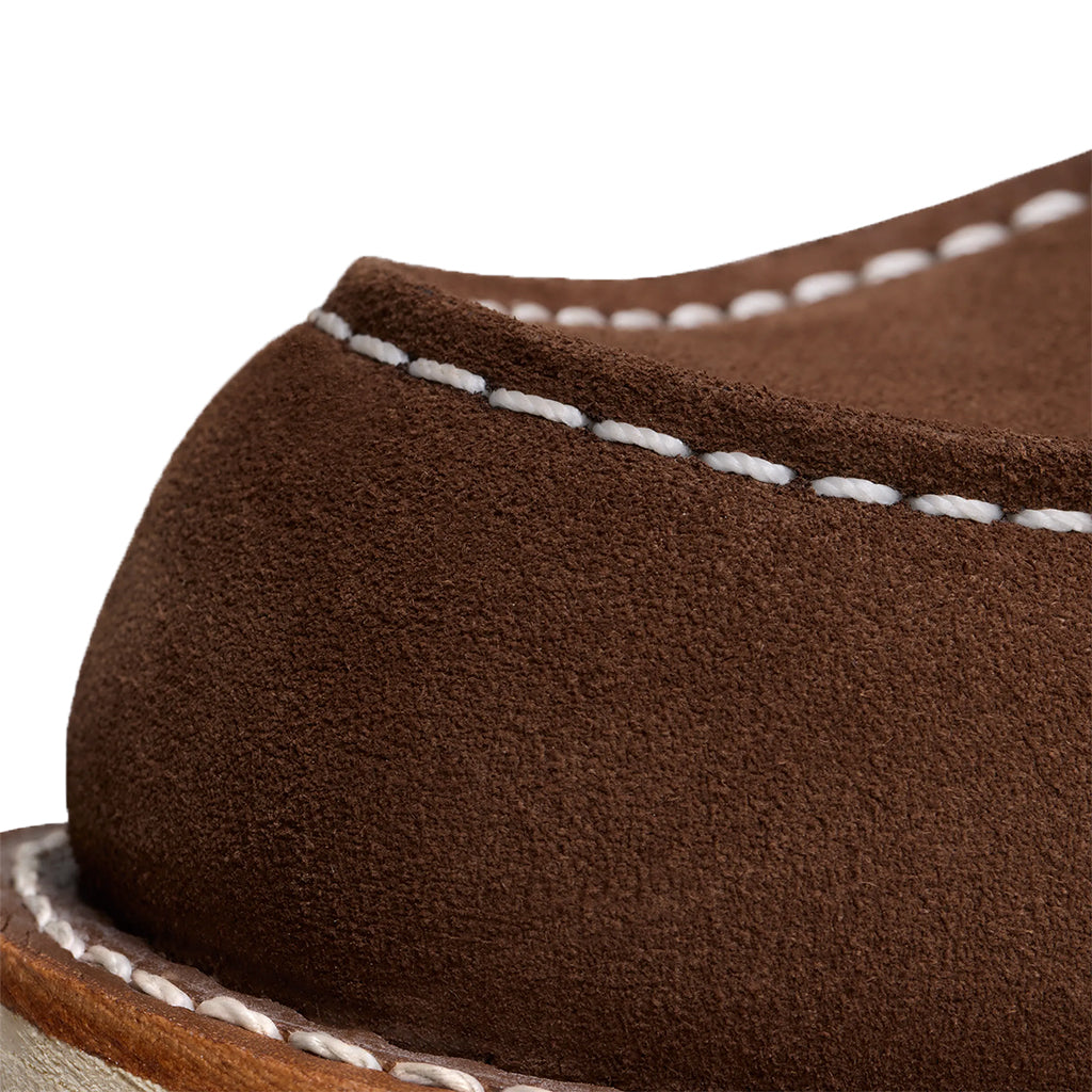 Close-up of a brown leather shoe with white stitching on a white background