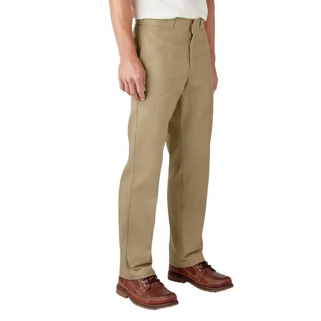 Person wearing beige pants and brown shoes on a white background