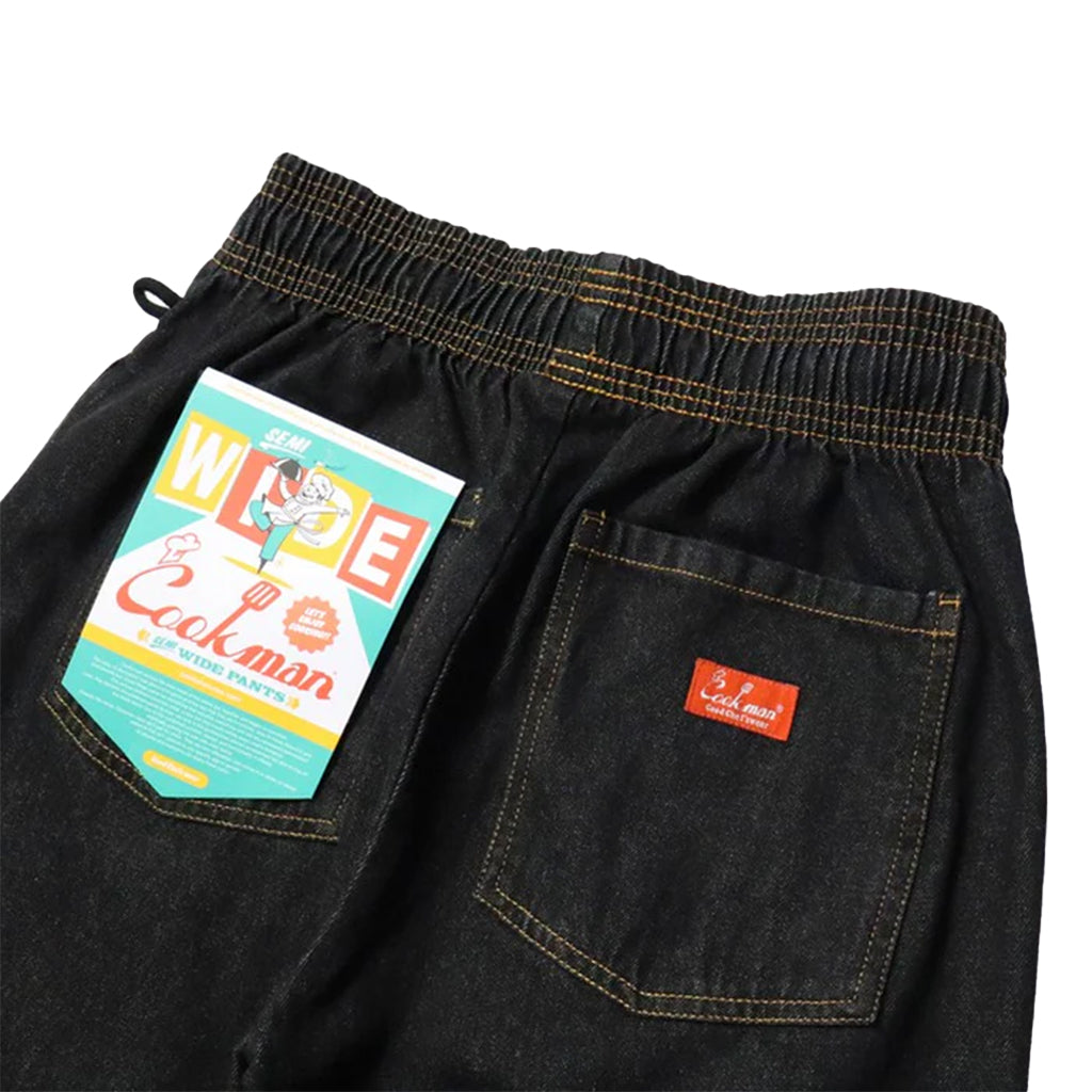 Black denim pants with a brand label on a white background