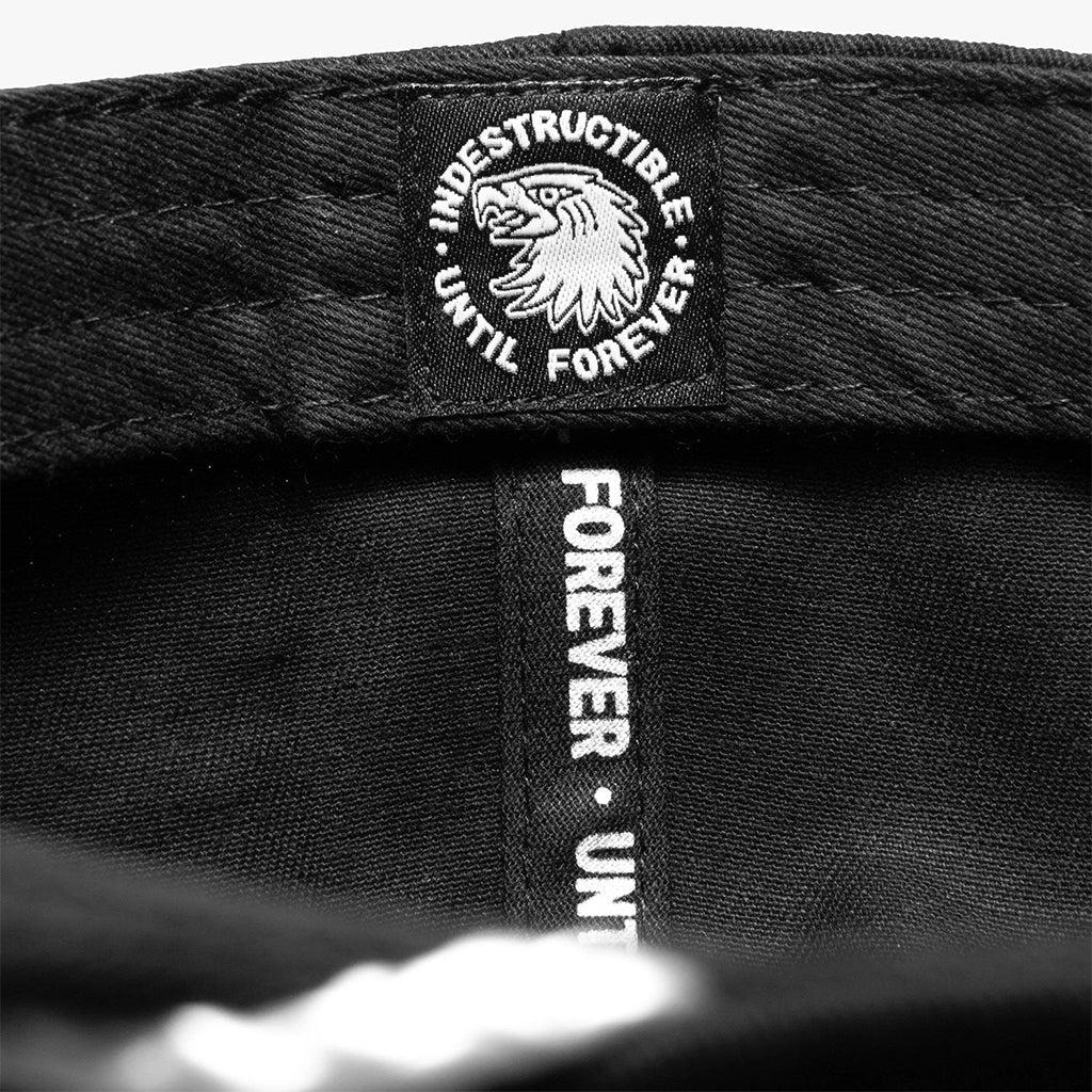 Close-up of a black cap with 'Indestructible Until Forever' branding.