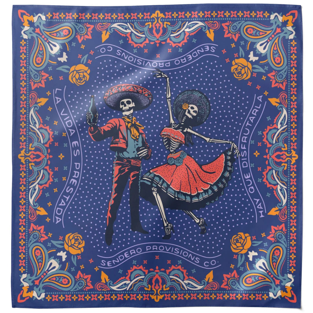A square bandana featuring a colorful Dia de los Muertos design with skeleton dancers, roses, and ornate borders on a dark blue background. The text 'SENDERO PROVISIONS CO' is printed around the border.