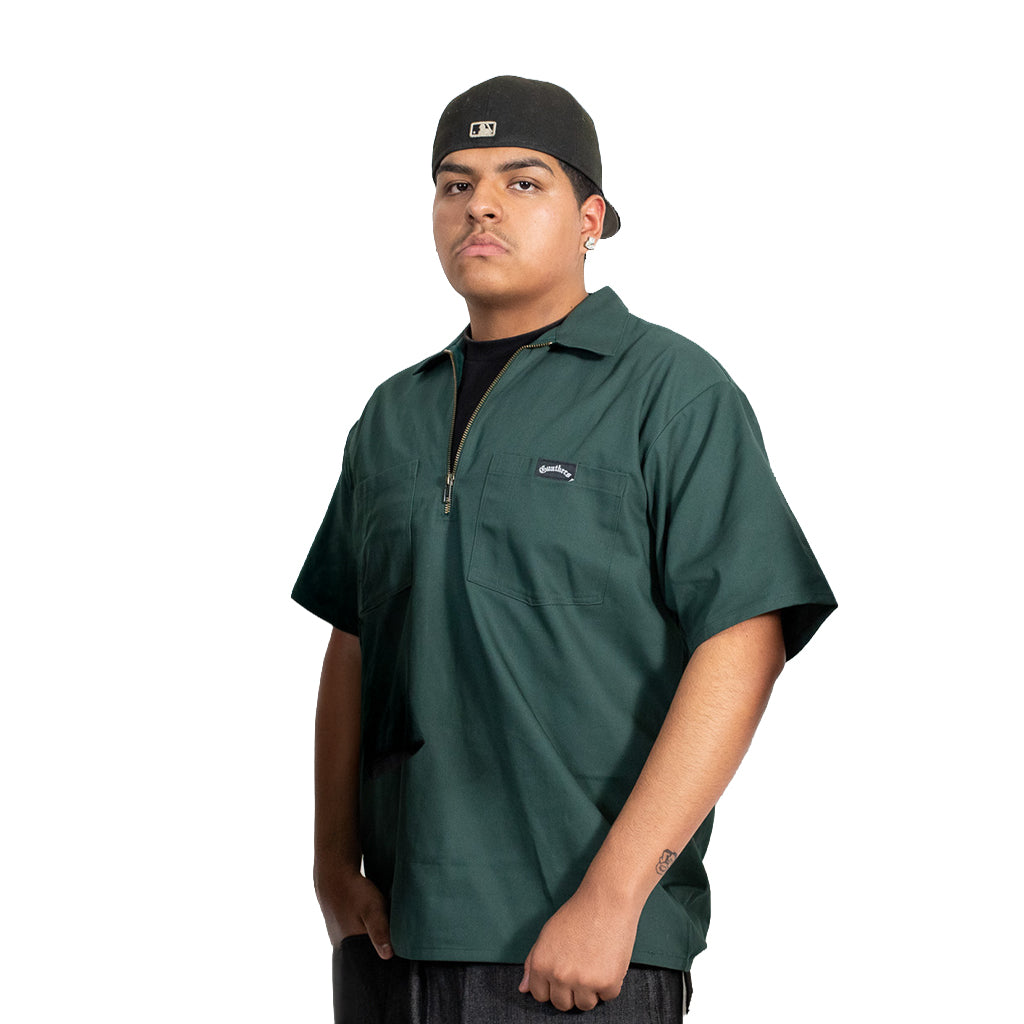 Person wearing a green shirt with a brand logo on a white background