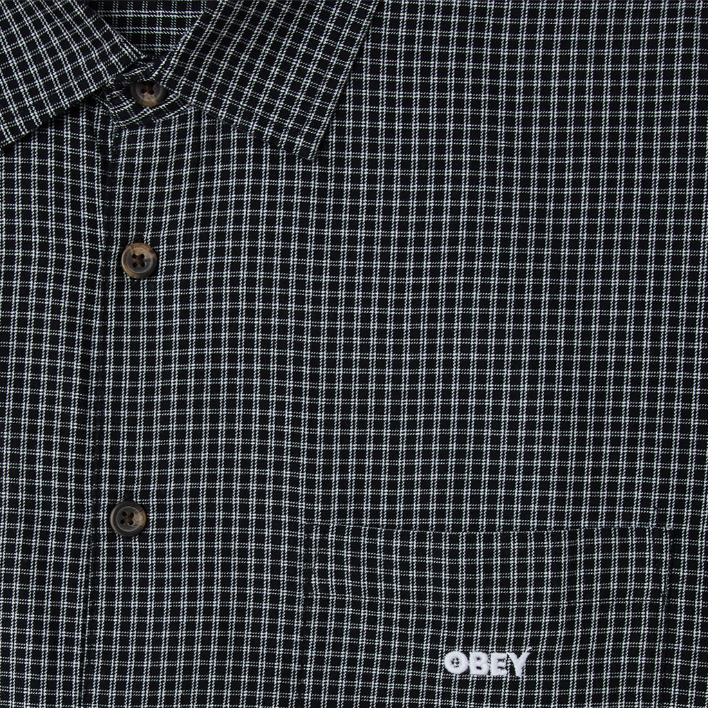 Close-up of a black and white checkered shirt with 'Obey' logo.