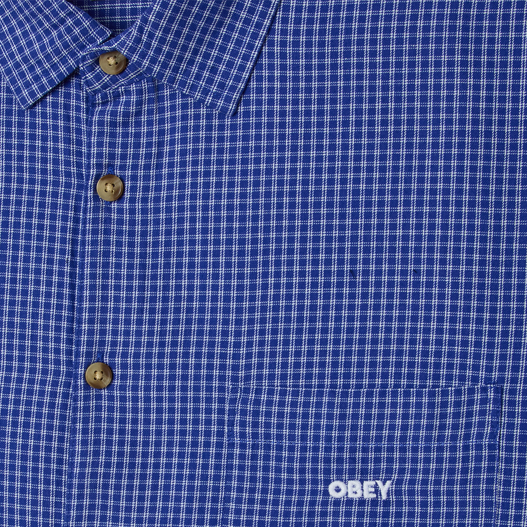 Close-up of a blue checkered shirt with 'Obey' logo