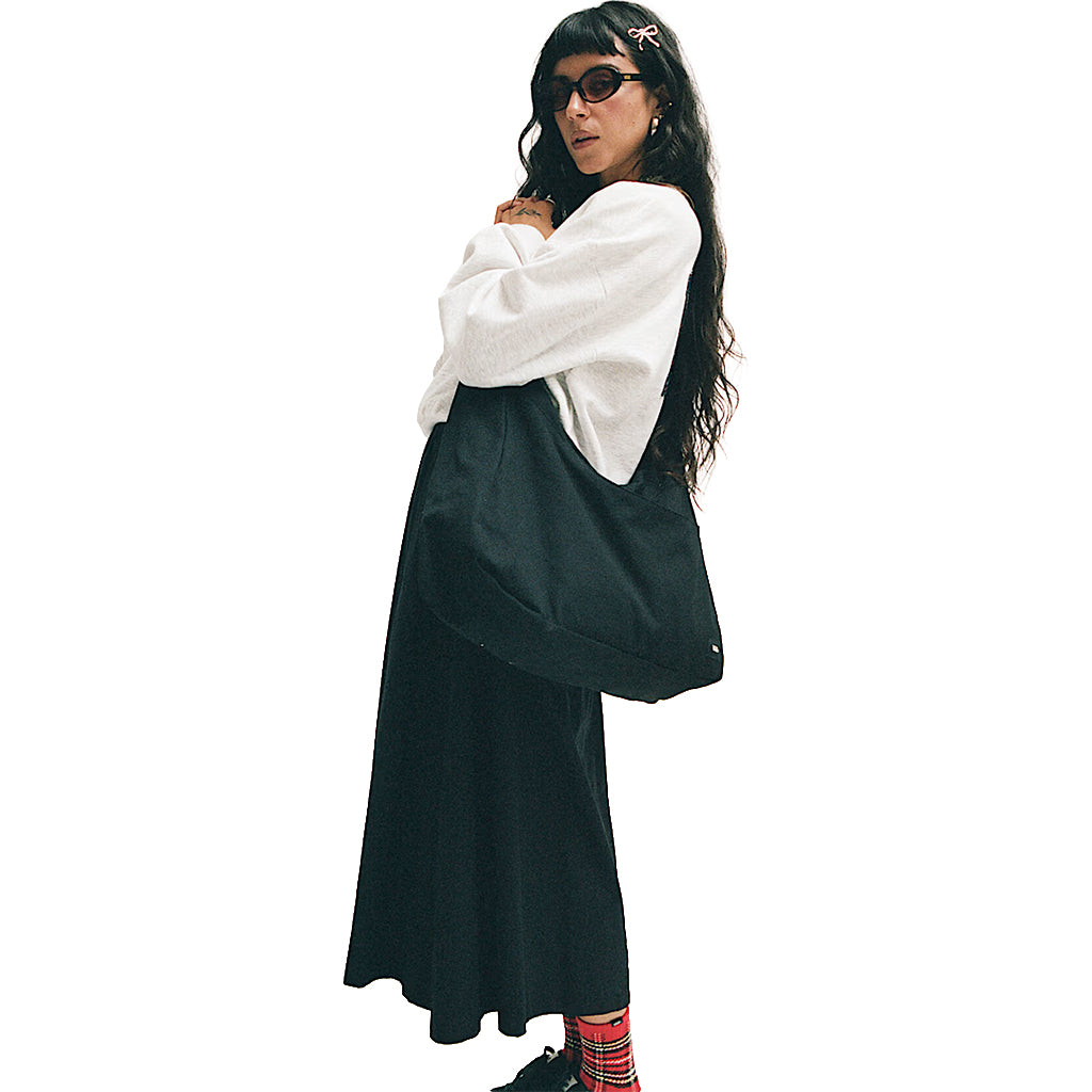 Person wearing a white shirt and black skirt modeling a Black Vans tote bag