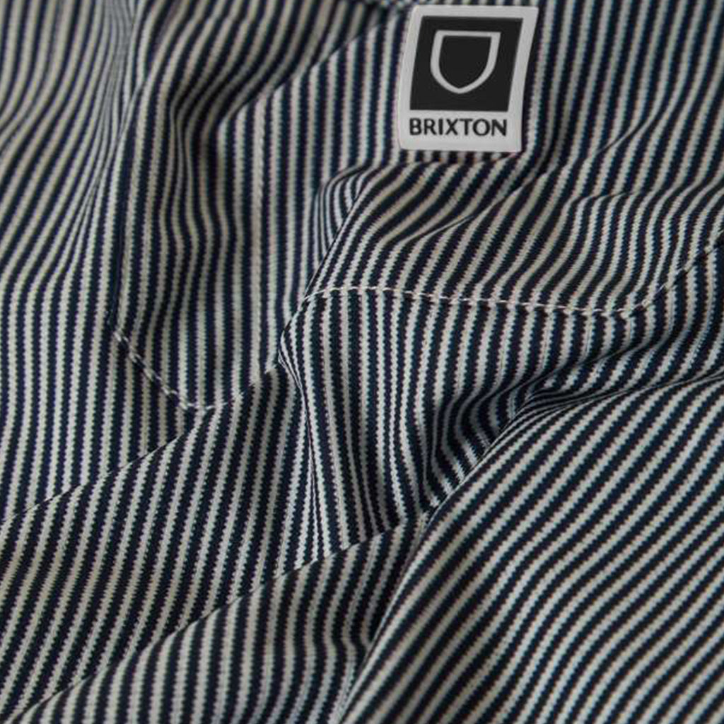 Close-up of a striped shirt with a Brixton logo on the collar.
