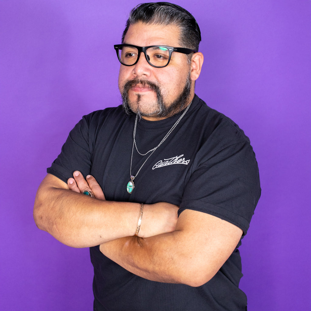 Man wearing a black t-shirt with visible branding against a purple background