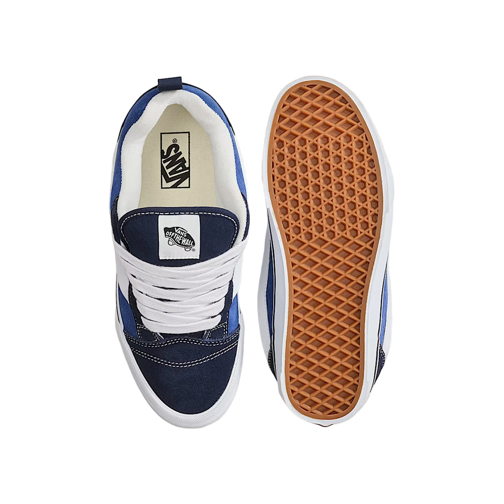 Navy and white sneaker with brown sole on a light gray background