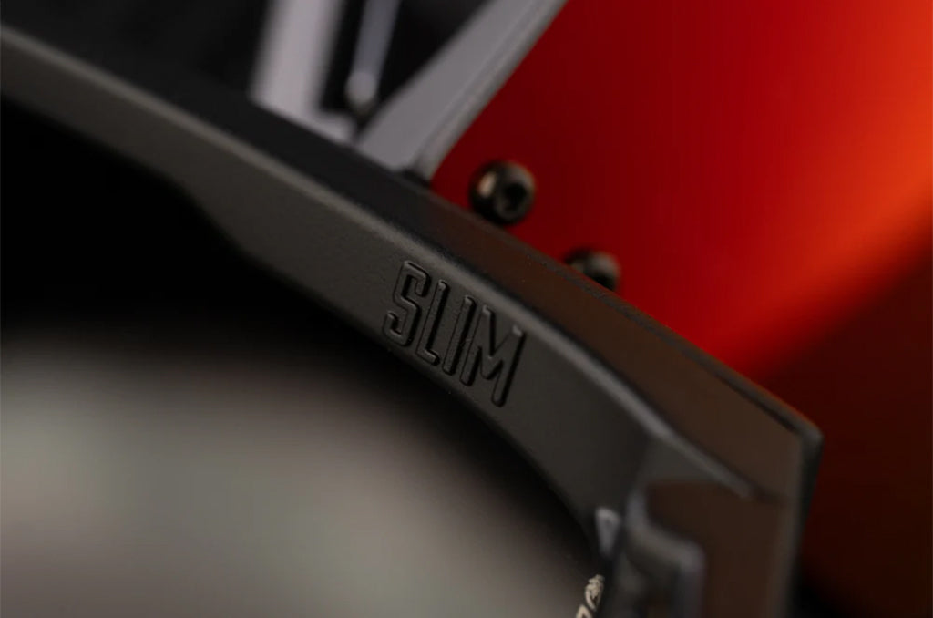 Close-up of a black frame with 'SLIM' branding against a blurred red background