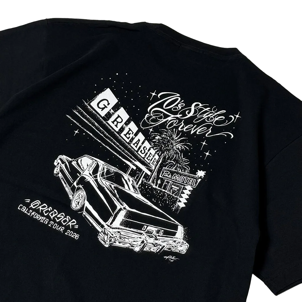 A close-up of a black short-sleeve T-shirt showing a large white graphic print on the back. The design features a retro car, a marquee reading 'G REASER', palm trees, stars, and stylized text including 'Do The Style Forever' and 'ORLANDO CALIFORNIA TOUR 2026'.