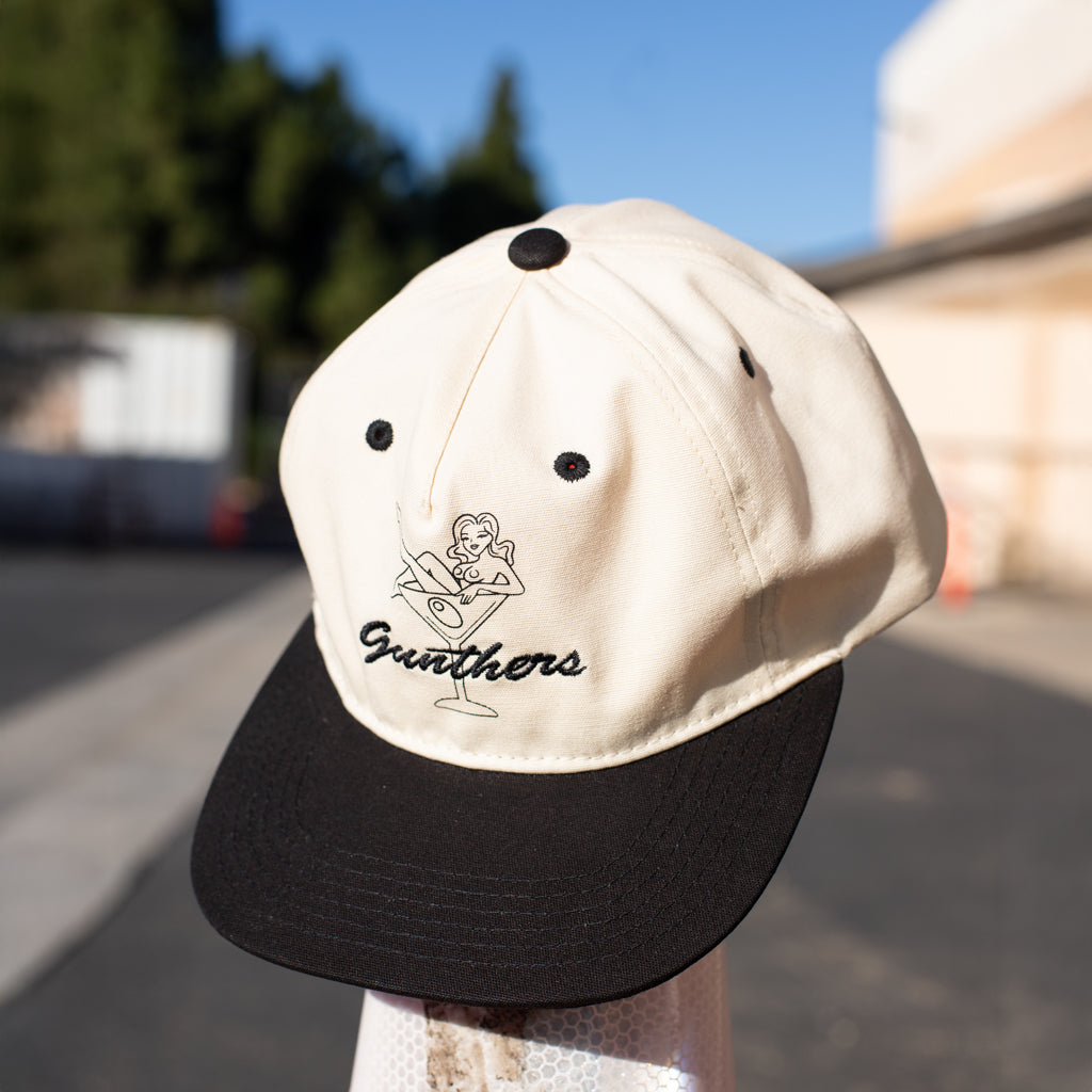 Cap with embroidered design of a woman in a martini glass and 'Gunthers' text.