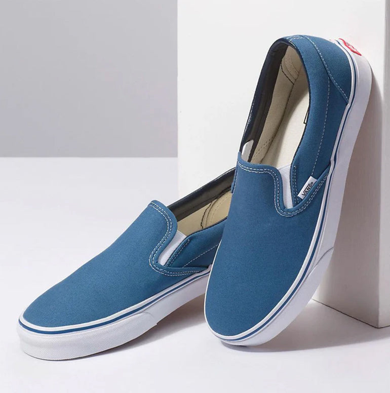 Blue slip-on shoes with white soles on a light gray background