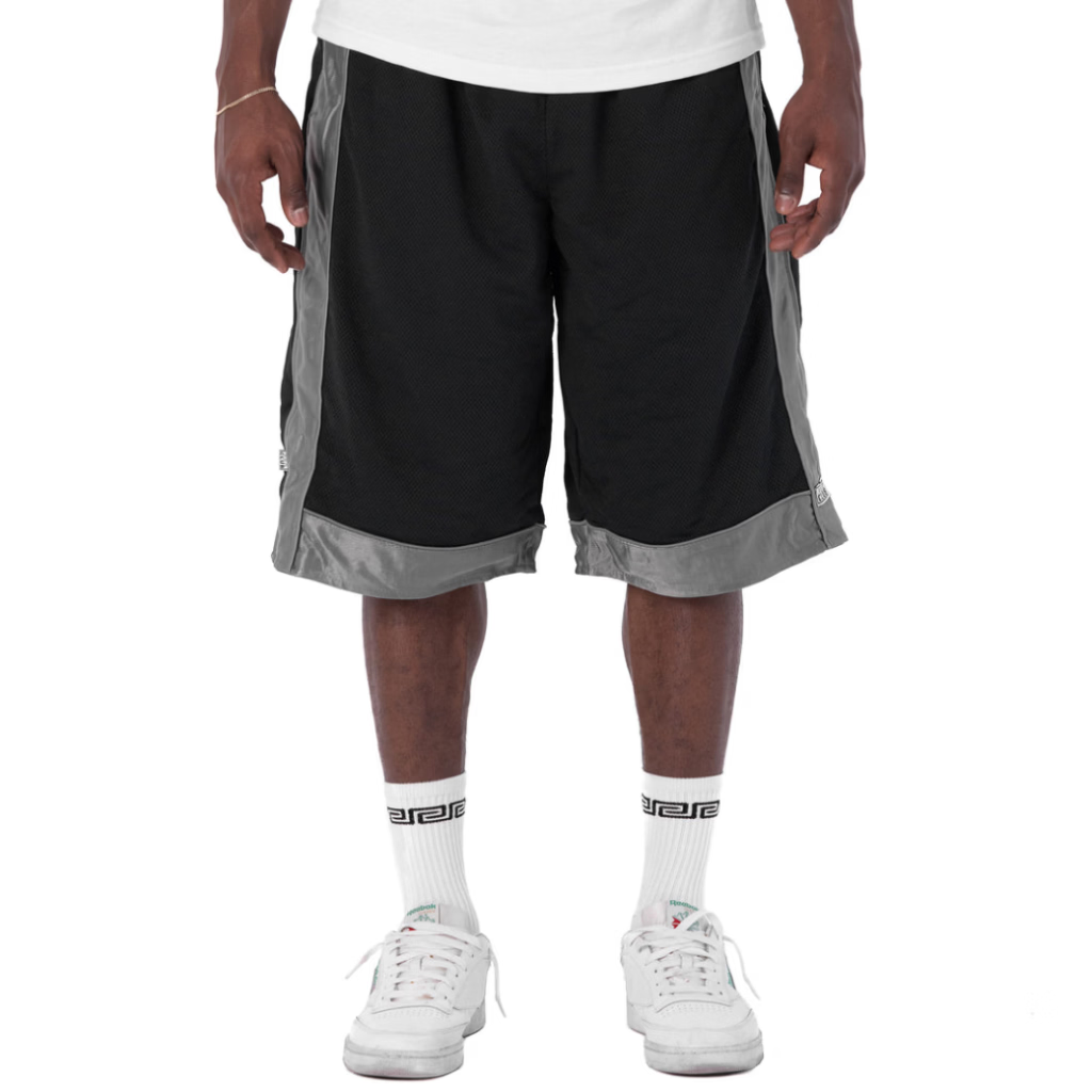 A person wearing black athletic shorts with gray side panels and hem trim, paired with a white t-shirt, white socks, and white sneakers, shown from the waist down on a white studio background.