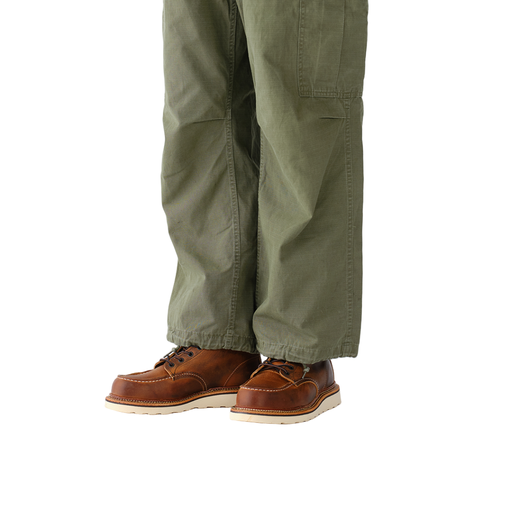 Brown leather shoes worn with green pants on a white background
