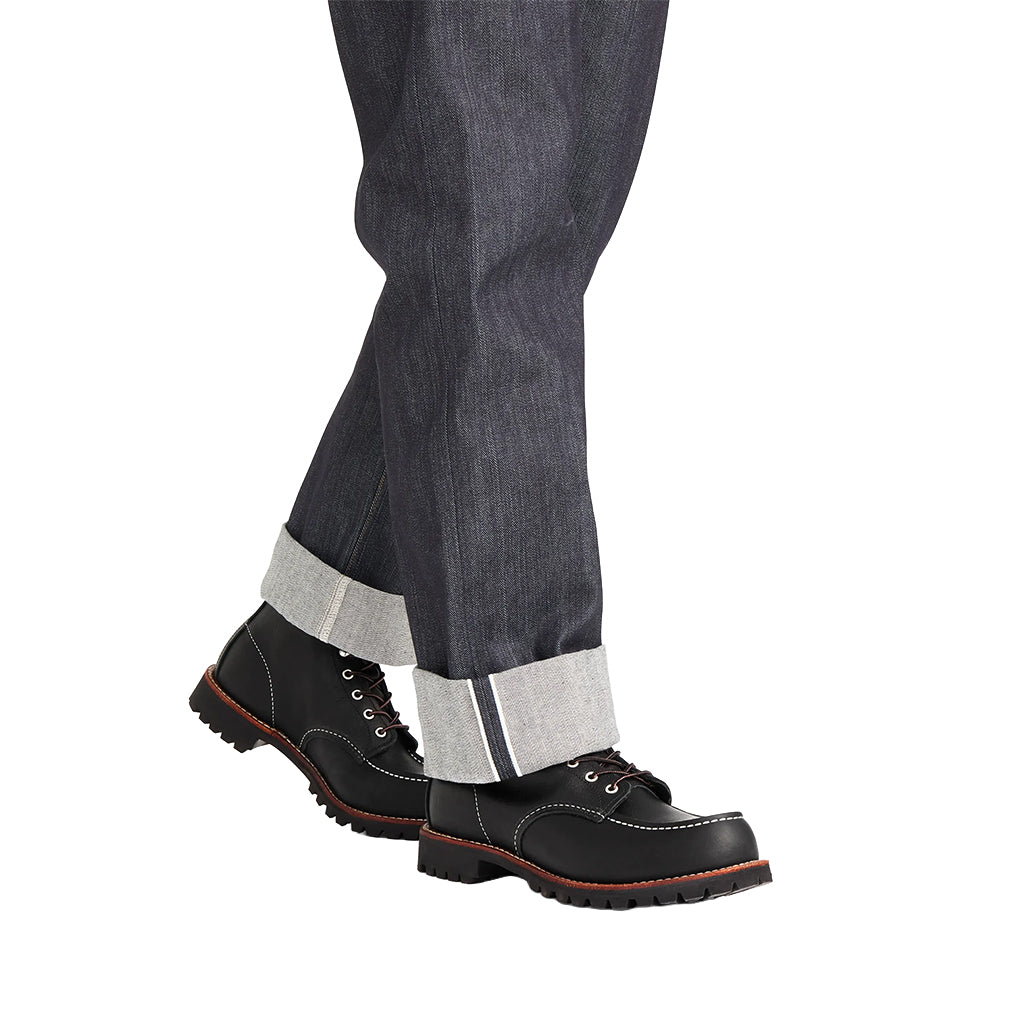 Black boots with white laces worn with gray pants on a white background