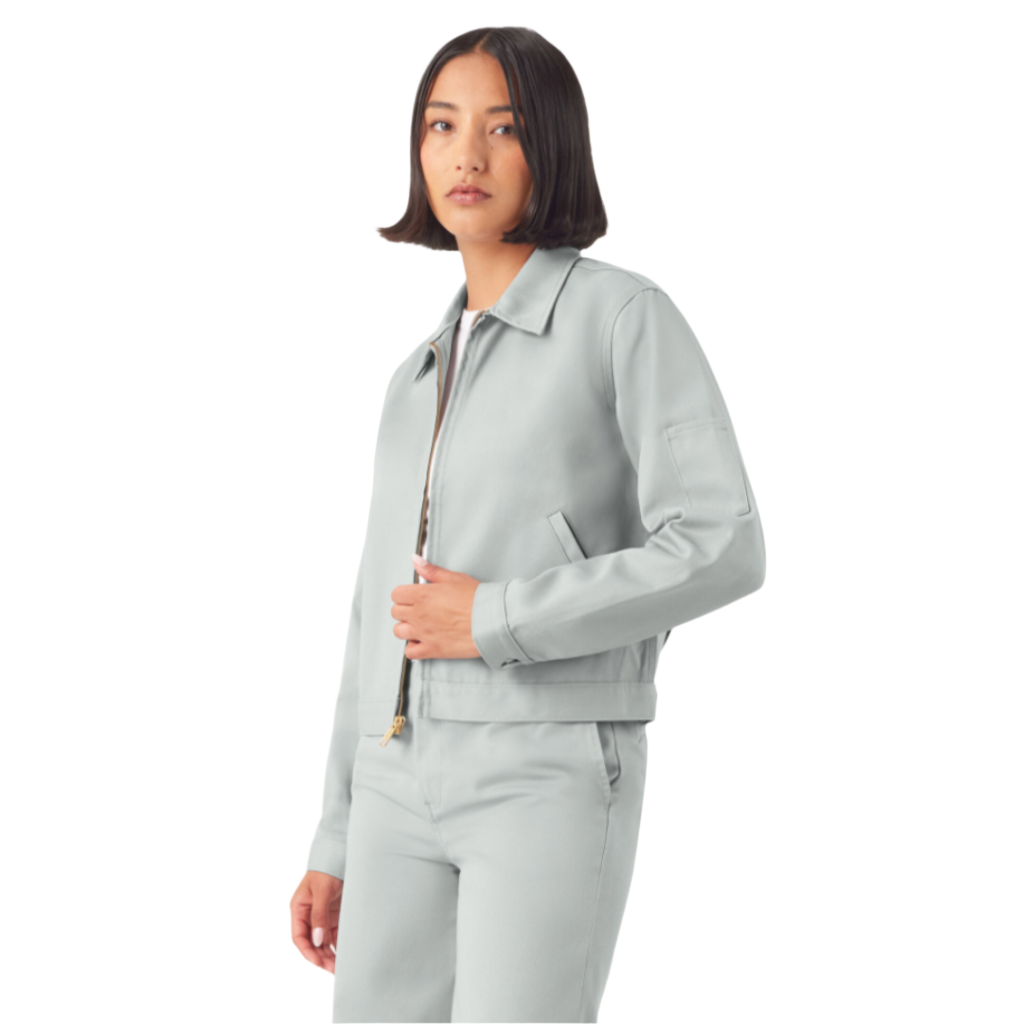 A woman wearing a cropped grey Eisenhower jacket with long sleeves, angled front welt pockets, and an adjustable waistband.