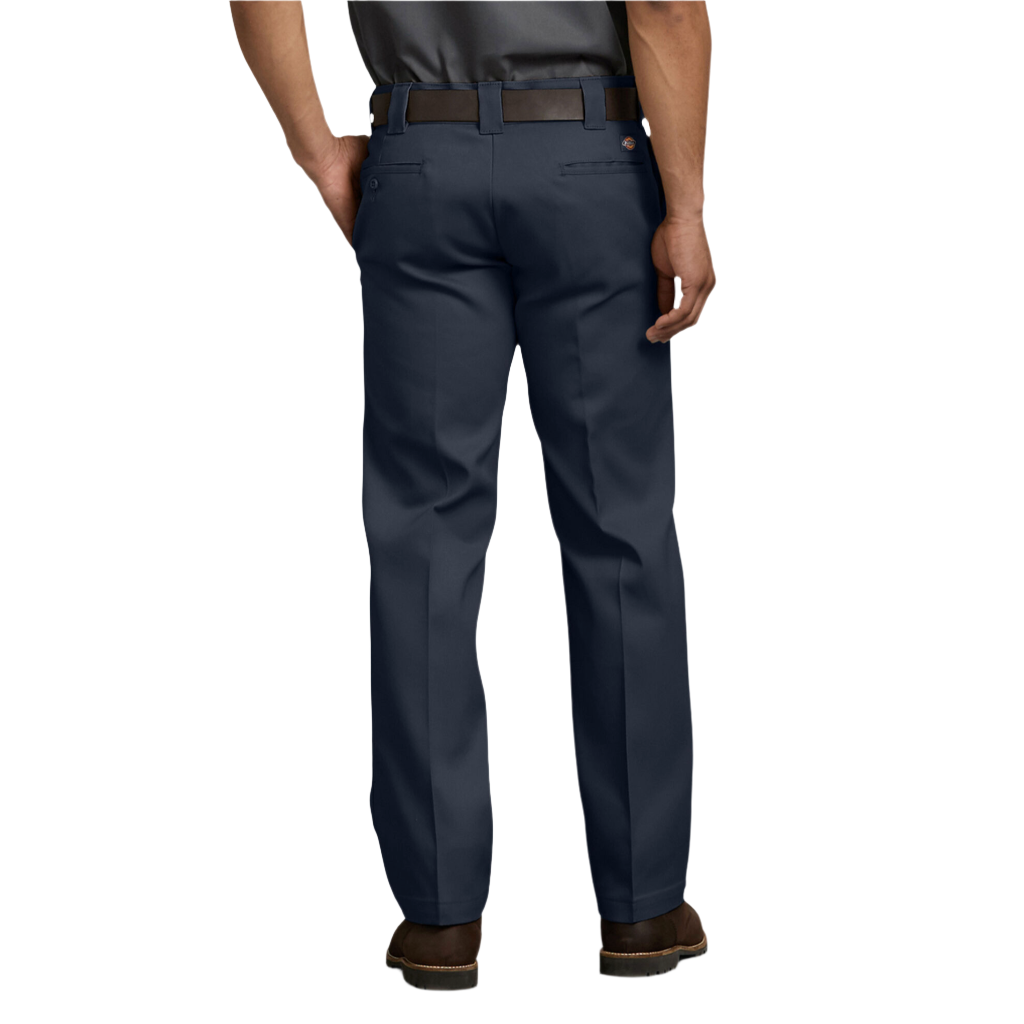 A man standing, wearing dark navy Dickies men's 873 flex slim fit work pants, a white shirt, and brown shoes.