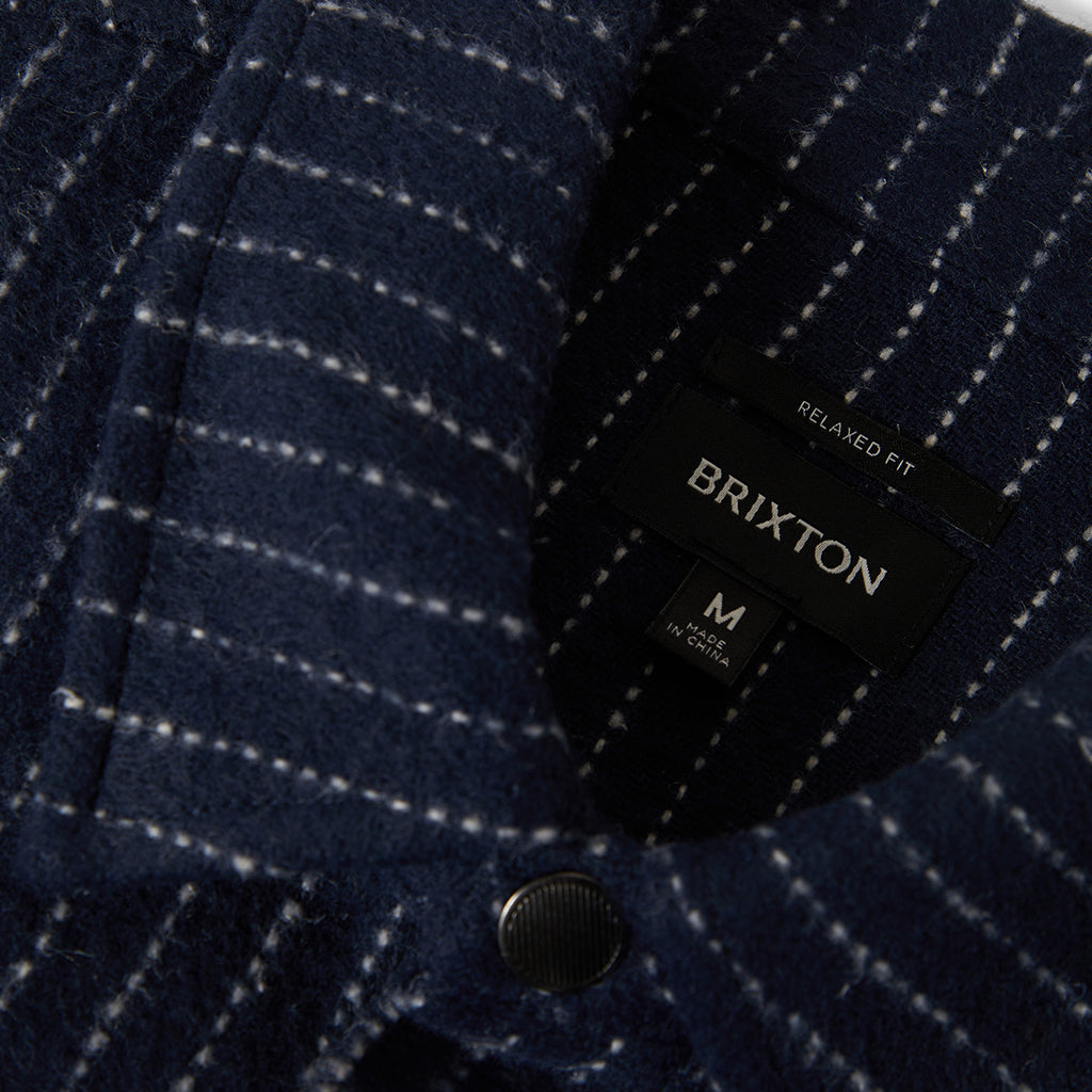 Navy checkered jacket with Brixton label on a dark background