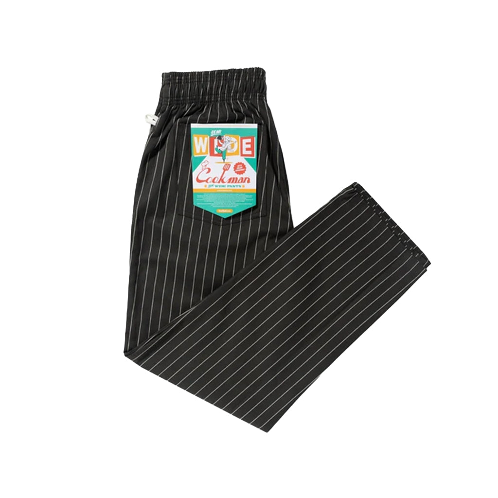 Black pinstripe pants with a colorful label on a white background
