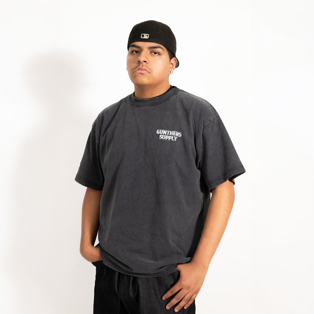 Person wearing a dark gray t-shirt with 'Gunters Supply' logo on a white background